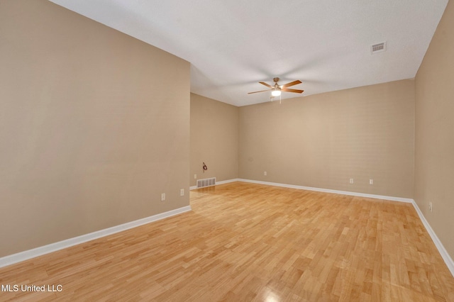 unfurnished room featuring a ceiling fan, visible vents, light wood-style flooring, and baseboards