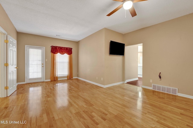 spare room with ceiling fan, light wood-type flooring, visible vents, and baseboards