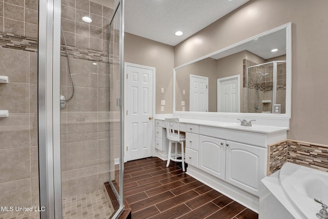 full bathroom featuring a stall shower, vanity, wood finish floors, a bath, and recessed lighting