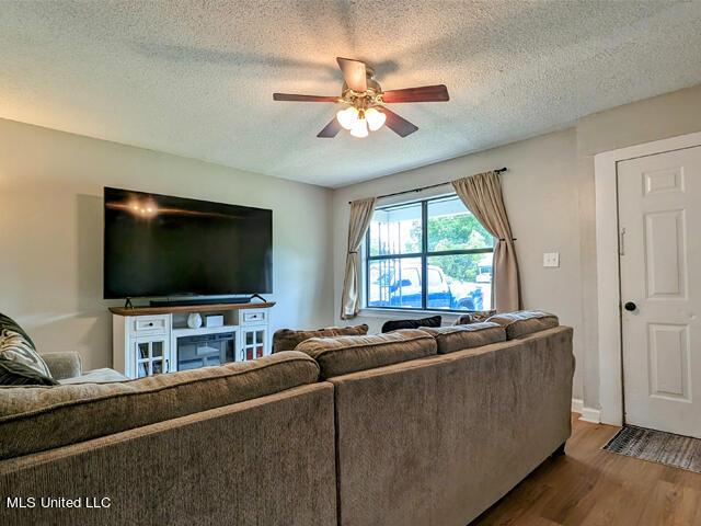 living room with hardwood / wood-style floors, ceiling fan, and a textured ceiling