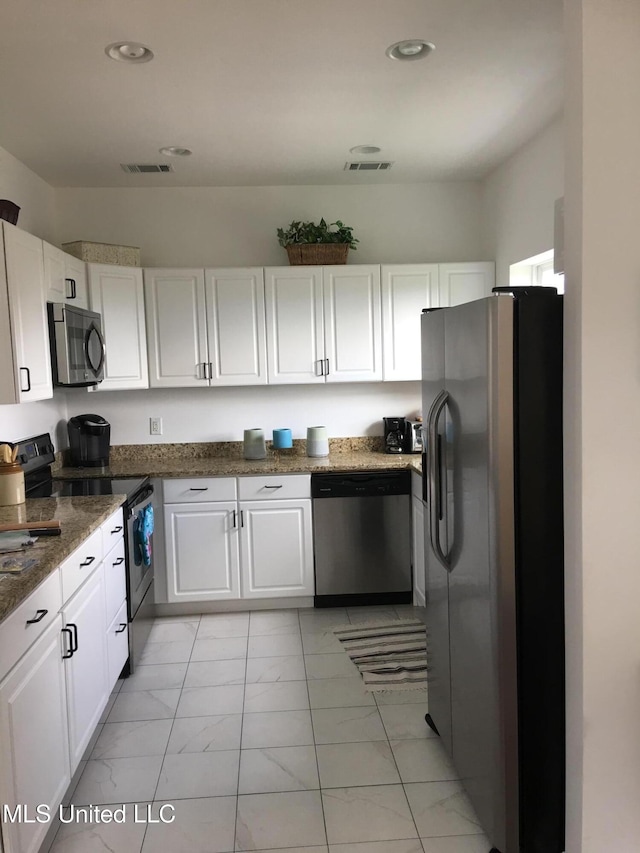 kitchen featuring white cabinets, stainless steel appliances, and dark stone counters