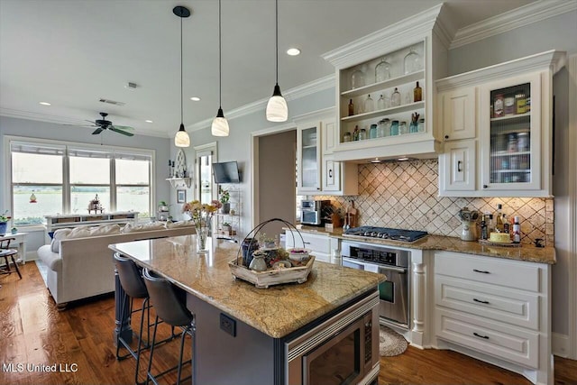 kitchen featuring appliances with stainless steel finishes, white cabinetry, hanging light fixtures, a kitchen breakfast bar, and a center island