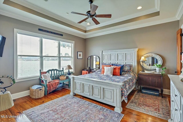 bedroom with a raised ceiling, wood-type flooring, ceiling fan, and crown molding