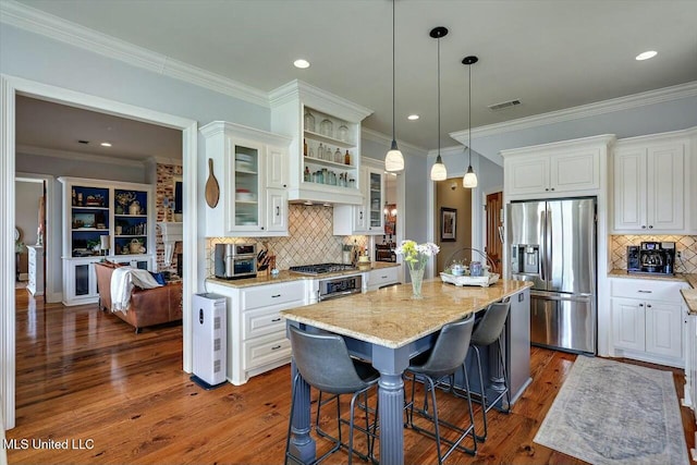 kitchen with a kitchen island, appliances with stainless steel finishes, a breakfast bar area, white cabinets, and light stone counters