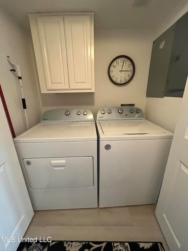 washroom featuring electric panel, light tile patterned flooring, separate washer and dryer, and cabinets