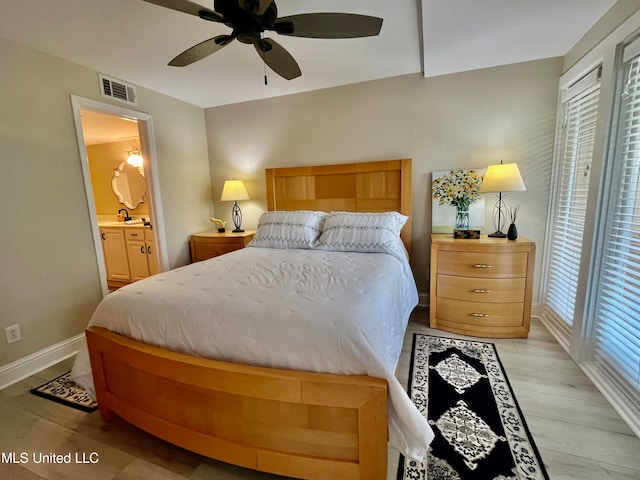 bedroom featuring light hardwood / wood-style floors, multiple windows, ensuite bath, and ceiling fan