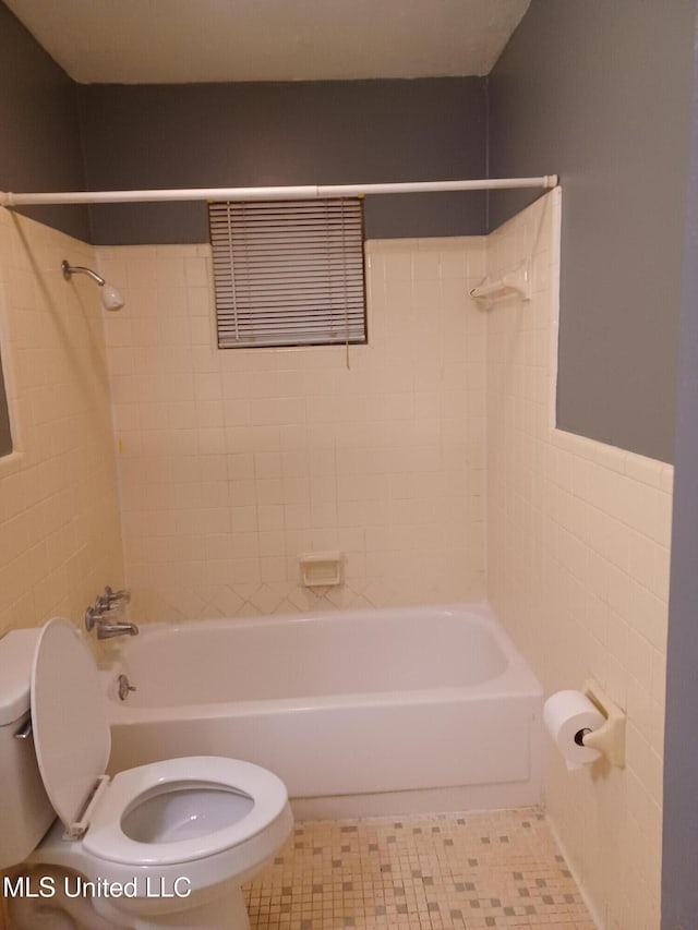 bathroom with tiled shower / bath, tile patterned floors, tile walls, and toilet