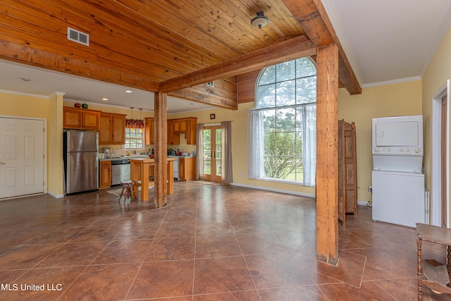 kitchen with stacked washer and dryer, dark tile patterned flooring, hanging light fixtures, stainless steel appliances, and wooden ceiling