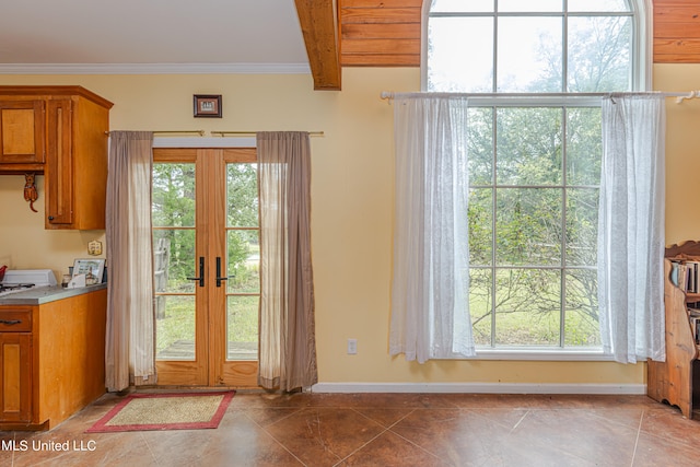 doorway to outside featuring beam ceiling, tile patterned floors, ornamental molding, and plenty of natural light