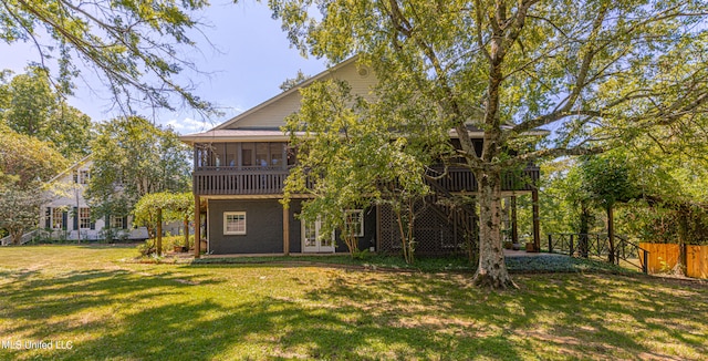 rear view of property with a deck, a sunroom, and a lawn