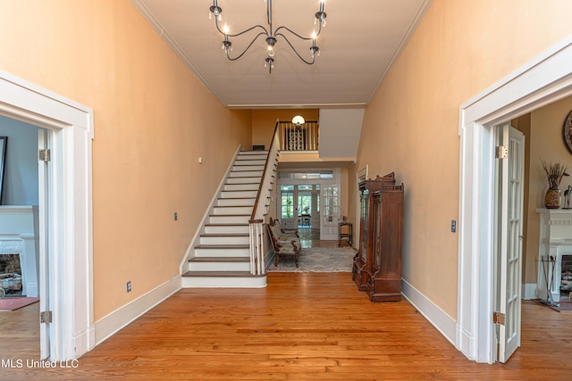 3775 Coker Rd, Madison, MS 39110 - entryway with a fireplace with raised hearth, crown molding, stairs, a chandelier, and wood finished floors