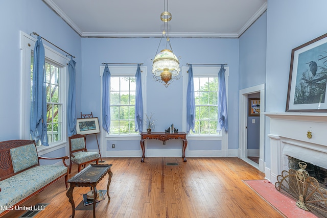 sitting room with a wealth of natural light, ornamental molding, and hardwood / wood-style flooring