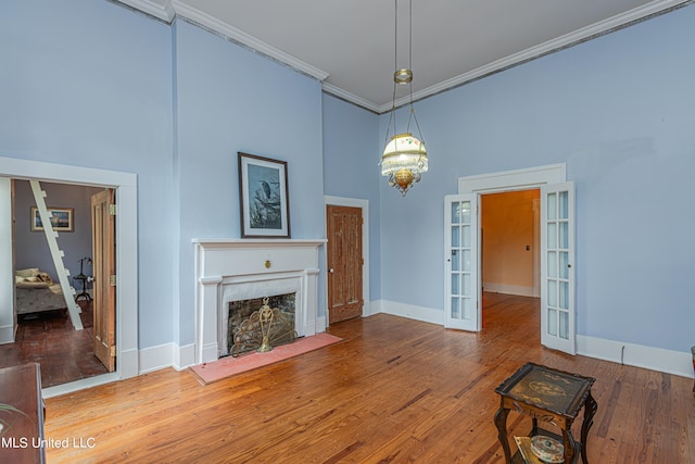 living room featuring hardwood / wood-style floors, crown molding, a high ceiling, and french doors