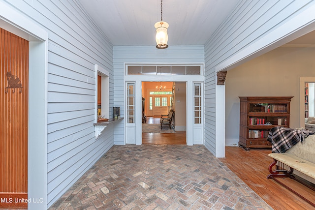 foyer with crown molding, wooden walls, and dark hardwood / wood-style flooring