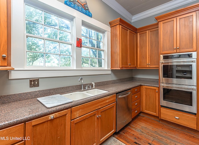 kitchen featuring appliances with stainless steel finishes, crown molding, hardwood / wood-style floors, and sink