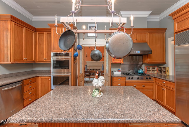 kitchen featuring dark stone countertops, stainless steel appliances, ornamental molding, and a kitchen island