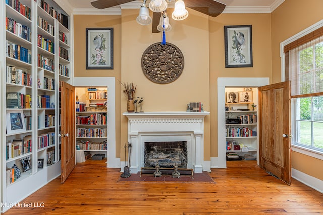 unfurnished living room featuring light hardwood / wood-style floors, ornamental molding, ceiling fan, and a wealth of natural light