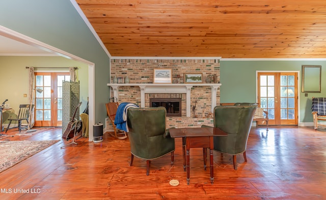 living room with french doors, hardwood / wood-style flooring, a brick fireplace, and plenty of natural light