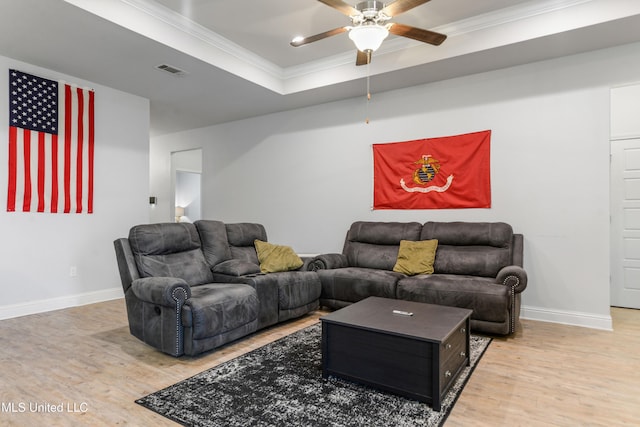 living room with hardwood / wood-style flooring, a tray ceiling, crown molding, and ceiling fan