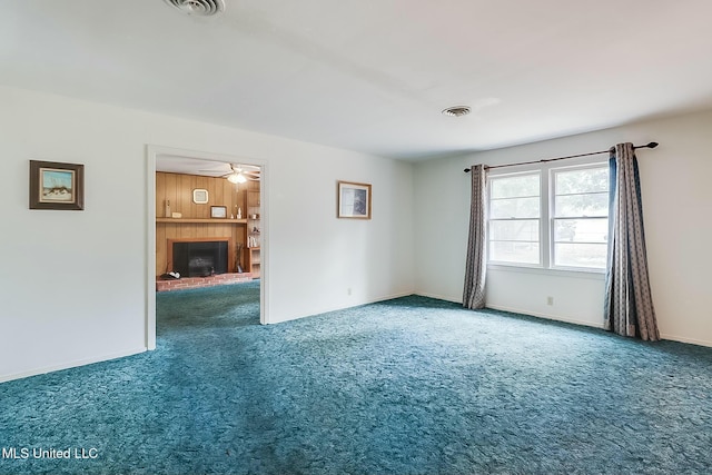 spare room with ceiling fan, a fireplace, and carpet flooring