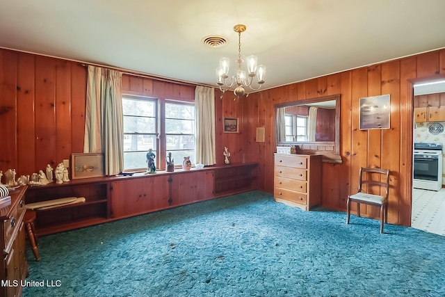 interior space with carpet flooring, an inviting chandelier, and wood walls