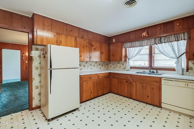 kitchen with sink, white appliances, and wood walls