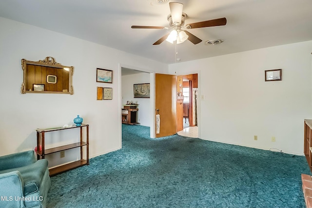 spare room with ceiling fan and dark colored carpet