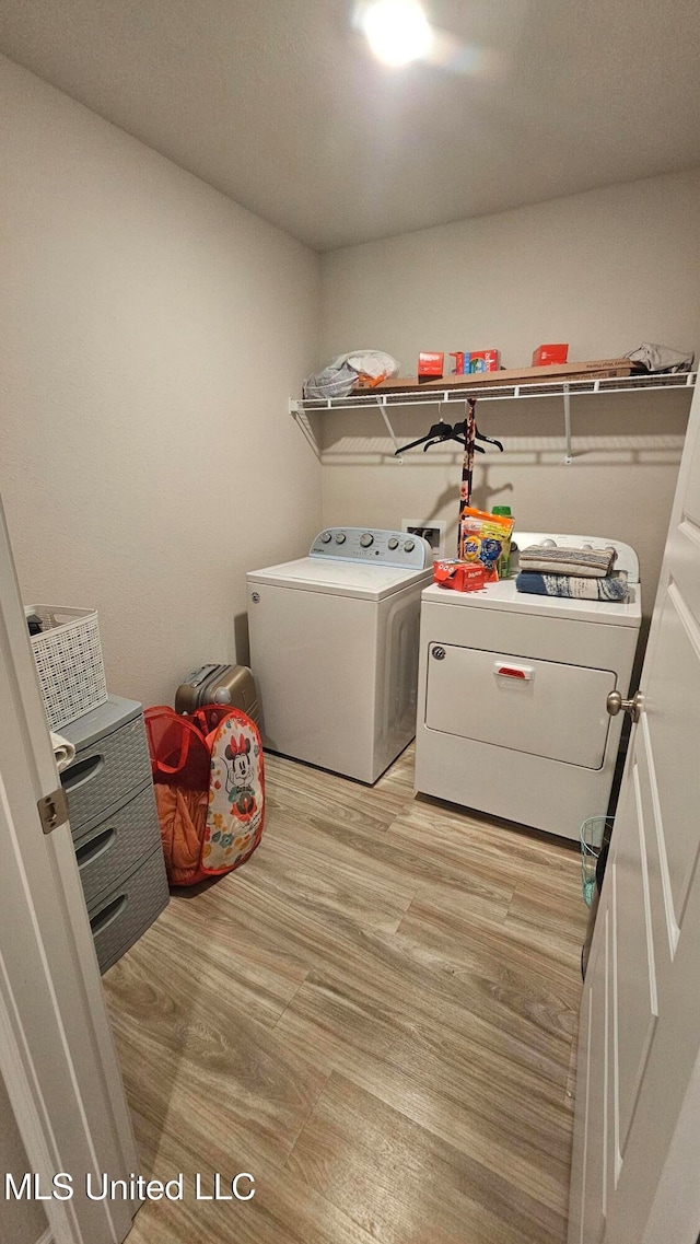 clothes washing area featuring light hardwood / wood-style flooring and washing machine and clothes dryer