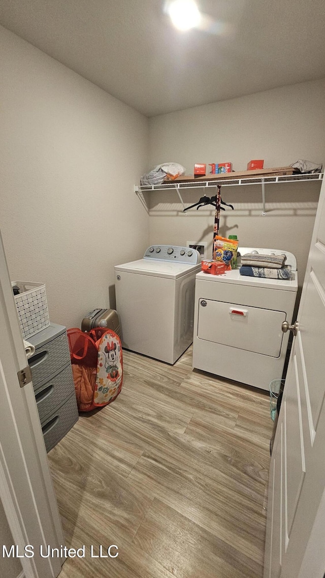 laundry room featuring separate washer and dryer, light wood-style flooring, and laundry area