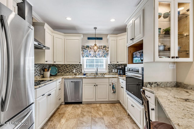 kitchen with tasteful backsplash, light stone counters, appliances with stainless steel finishes, sink, and decorative light fixtures