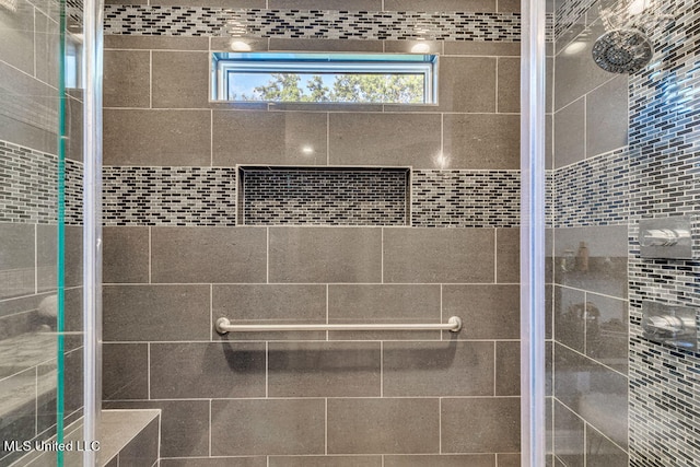 bathroom featuring a shower with shower door and a wealth of natural light