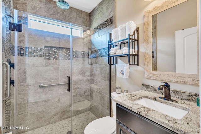 bathroom with vanity, a shower with shower door, and toilet