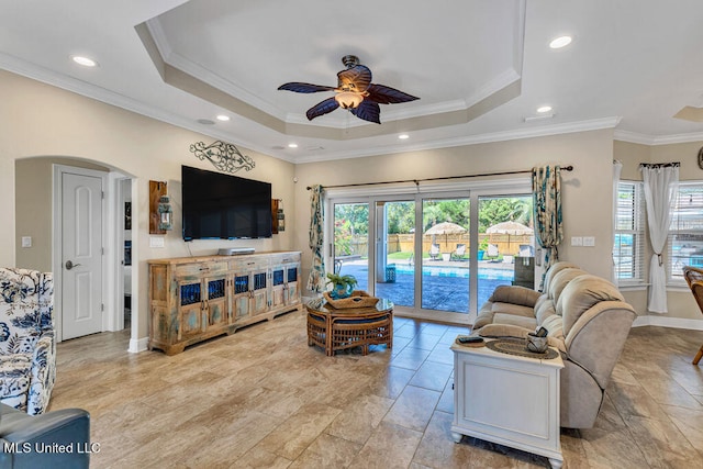 living room featuring a wealth of natural light, ornamental molding, a tray ceiling, and ceiling fan