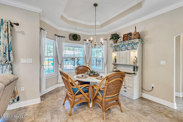 dining space with a raised ceiling, ornamental molding, and an inviting chandelier