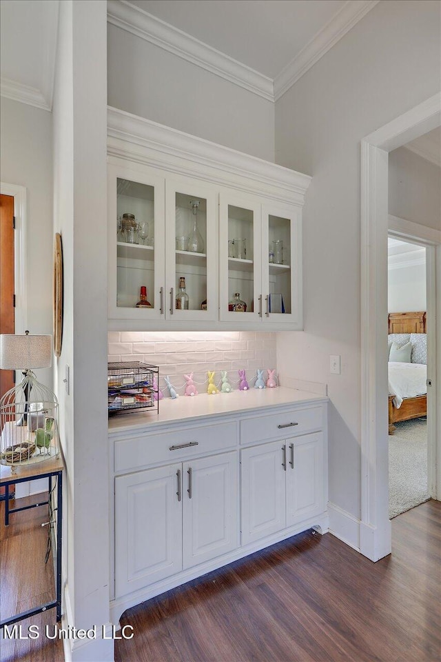 bar featuring tasteful backsplash, white cabinetry, dark hardwood / wood-style floors, and ornamental molding