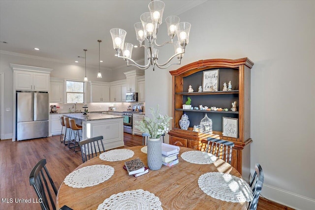 dining area featuring a chandelier, sink, dark wood-type flooring, and ornamental molding