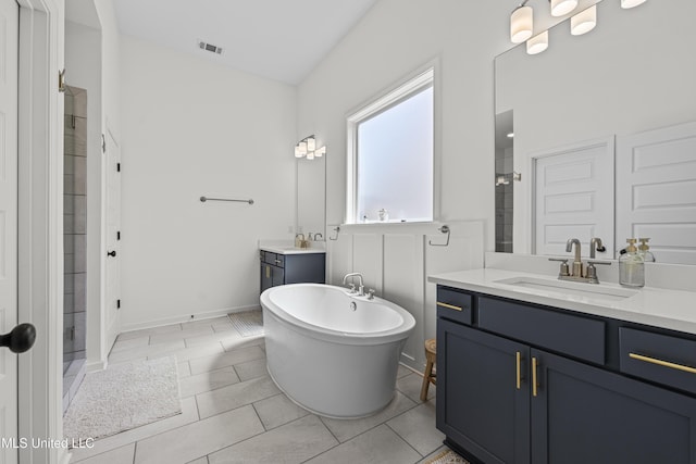 bathroom with visible vents, a freestanding tub, a sink, a shower stall, and two vanities