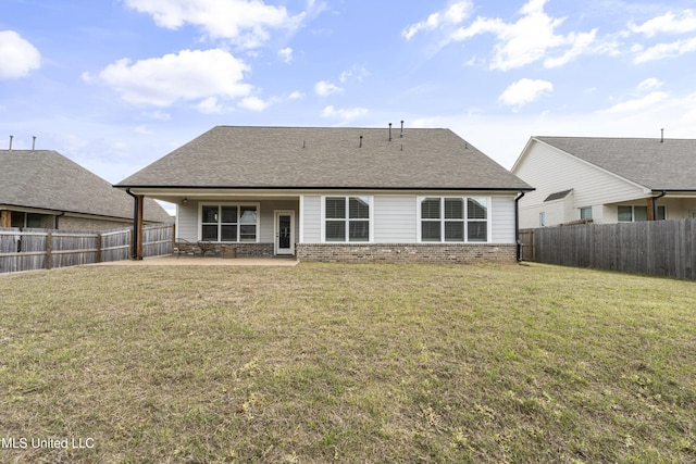 back of house featuring a yard, a patio area, a fenced backyard, and brick siding
