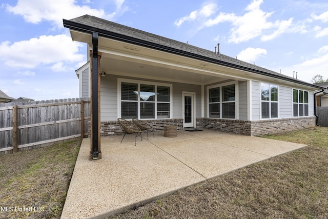 back of property with brick siding, fence, and a patio area
