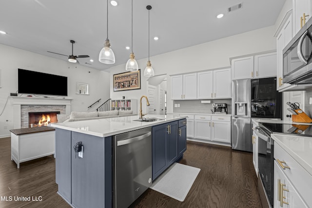 kitchen with visible vents, a sink, a center island with sink, blue cabinetry, and stainless steel appliances