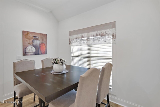 dining space with vaulted ceiling, a wealth of natural light, and hardwood / wood-style floors