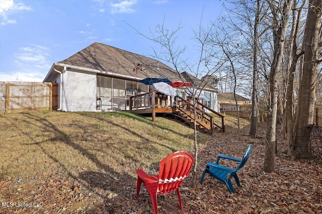 exterior space featuring a lawn, a deck, and a sunroom