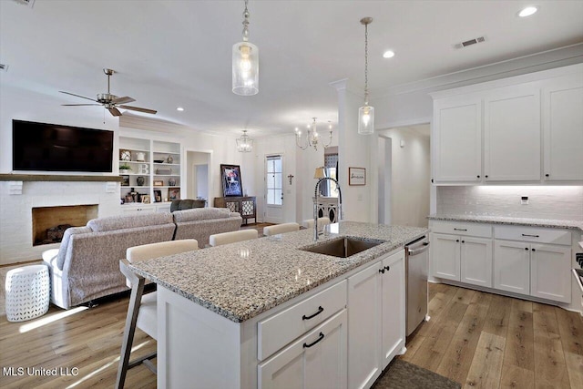 kitchen featuring sink, white cabinets, pendant lighting, and light stone counters