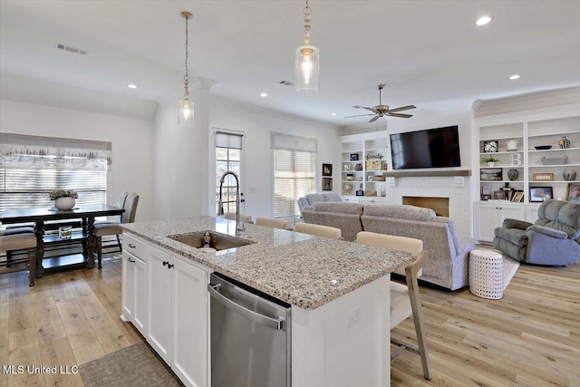 kitchen with dishwasher, decorative light fixtures, an island with sink, white cabinetry, and sink