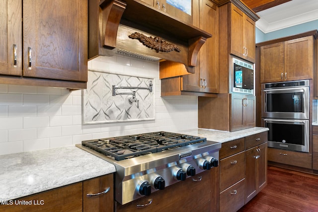 kitchen with dark wood-type flooring, backsplash, appliances with stainless steel finishes, and premium range hood