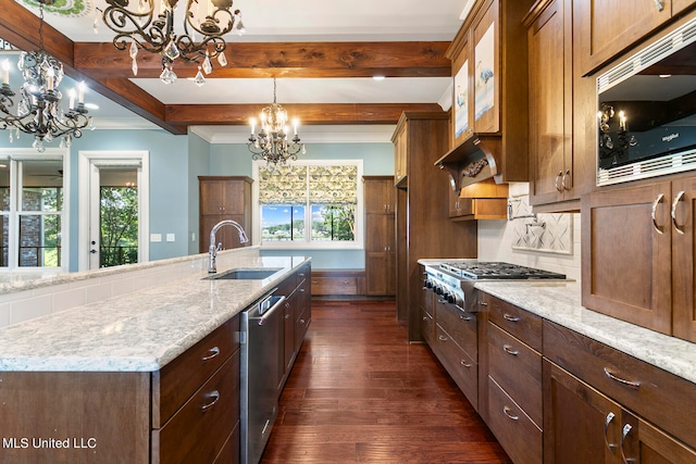 kitchen featuring dark wood-type flooring, hanging light fixtures, stainless steel appliances, a center island with sink, and sink