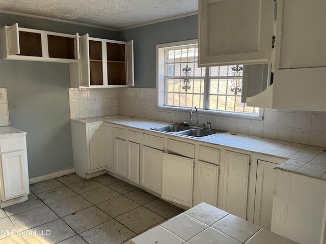 2115 Powers Ave, Jackson, MS 39213 - kitchen with decorative backsplash, a textured ceiling, tile counters, light tile patterned floors, and ornamental molding