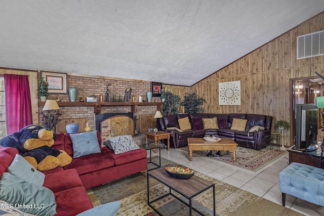 living room with wooden walls, visible vents, lofted ceiling, tile patterned floors, and a textured ceiling