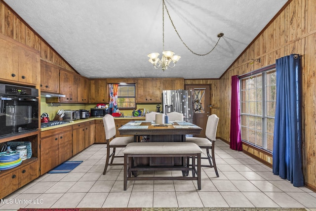 dining room featuring vaulted ceiling, light tile patterned floors, and wood walls