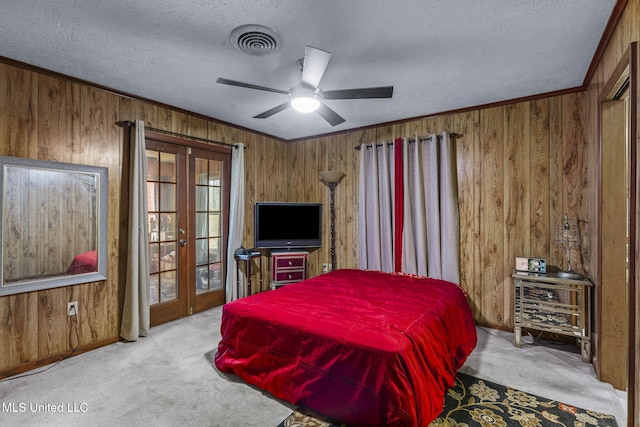 carpeted bedroom featuring french doors, visible vents, ornamental molding, wooden walls, and a textured ceiling